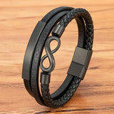 Infinity Leather Bracelet For Men Black multi-strand leather bracelet with braided and smooth leather bands, matte black metal plates, and an infinity symbol clasp, displayed on a wooden surface.